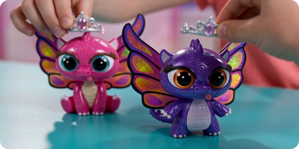 Hands styling dragons with wings and tiaras